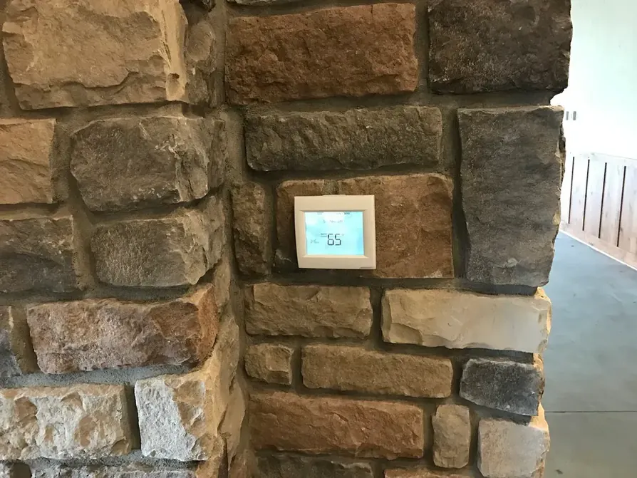 A smart thermostat installed in a stone accent wall by All Around Mechanical