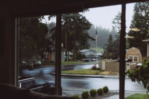 Pacific Northwest home in rain with cozy interior visible through window